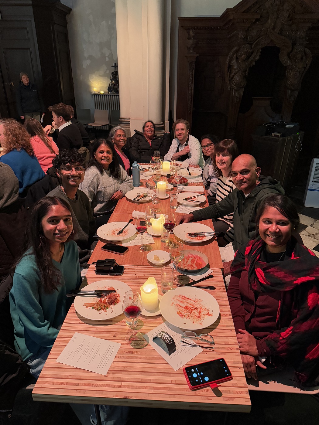 Lakshmee and her entire family along with Chef Seppe Nobels and Tourism Flanders staff member Greet Vandenrijt seated at a long banquet dinner table. They’re all smiles for the camera.